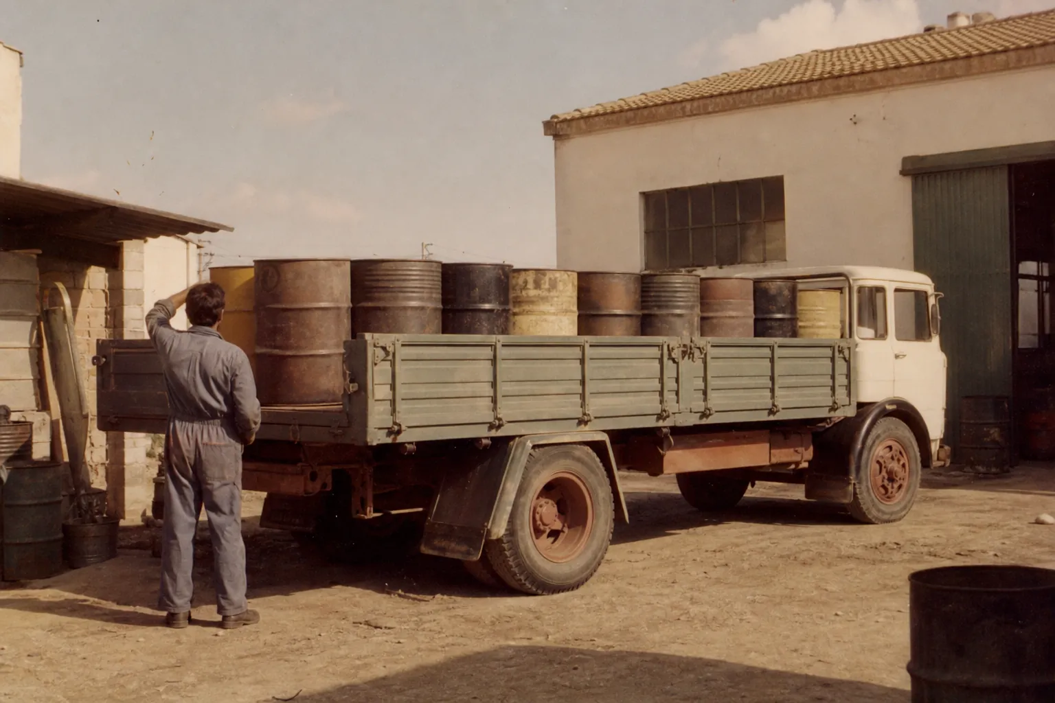 Fotografía de época de un camión cargado con bidones de aceite en los años setenta