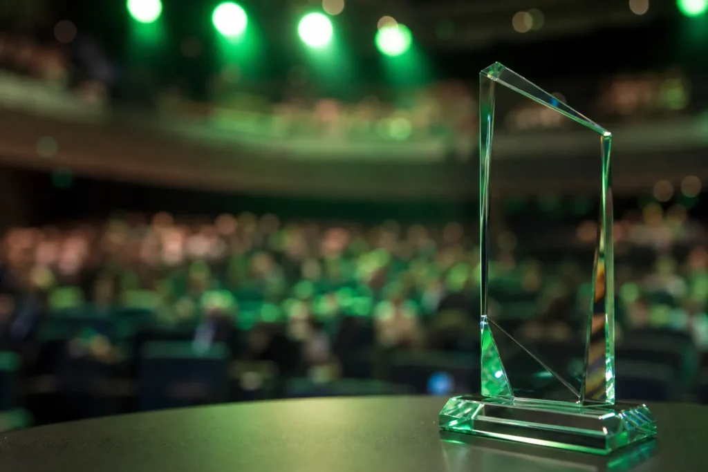 Trofeo de cristal sobre un escenario iluminado en verde