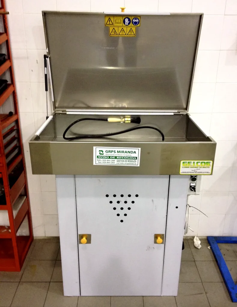 Máquina lavapiezas con tapa en un taller